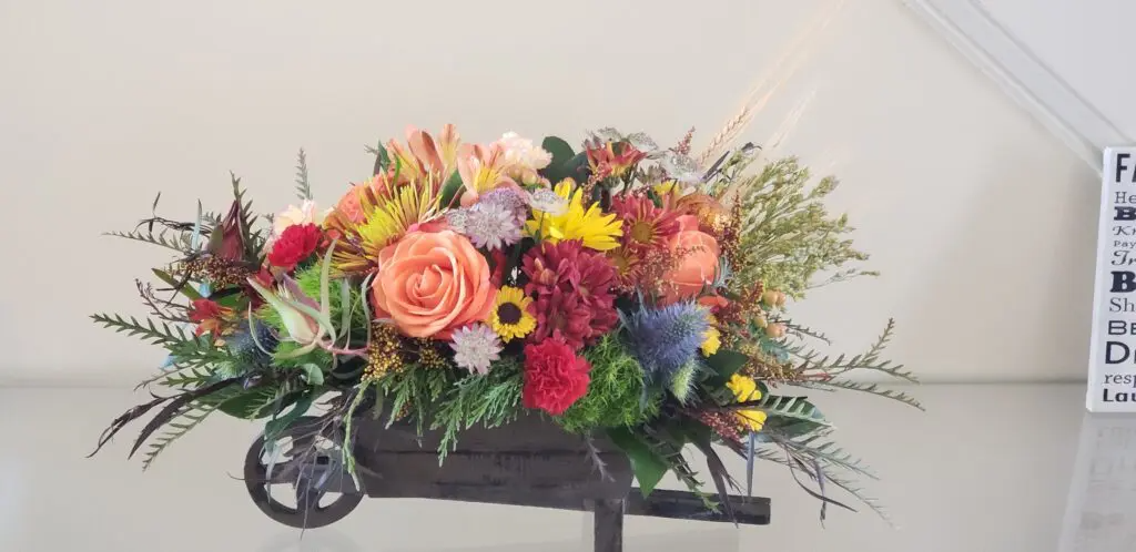 A wheelbarrow filled with flowers is sitting on a table.