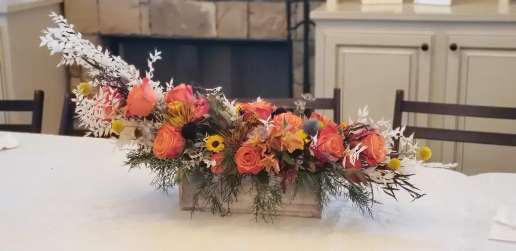 A wooden box filled with flowers is sitting on a table.