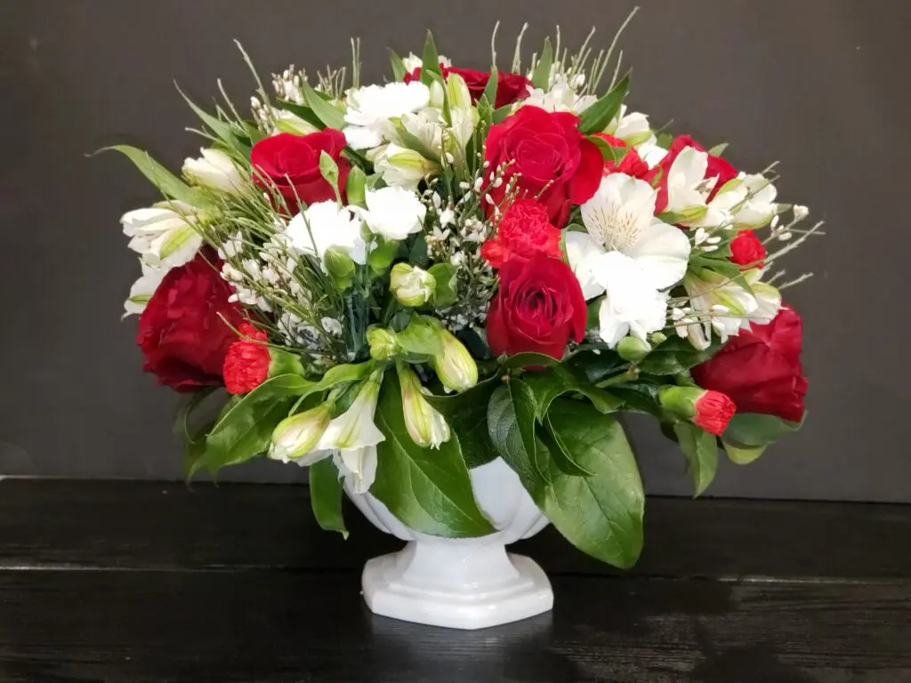 A vase filled with red and white flowers on a table.