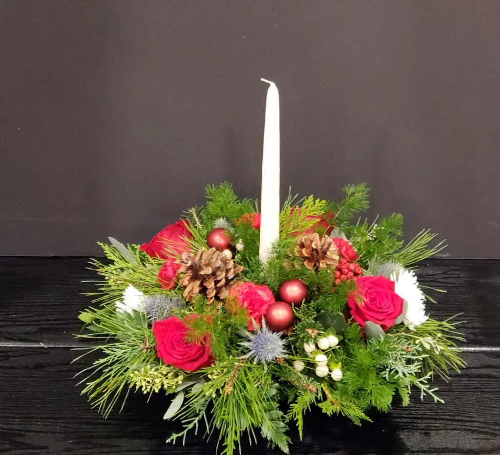 A christmas centerpiece with a candle in the middle