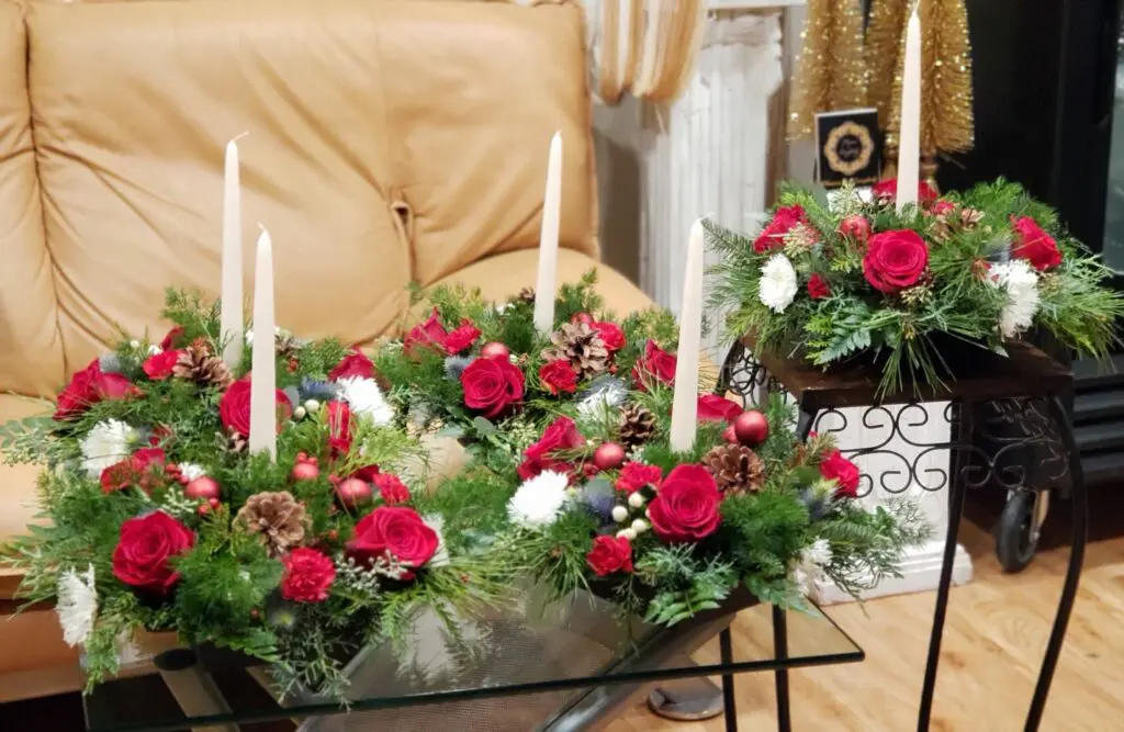 A table with flowers and candles on it in front of a couch.