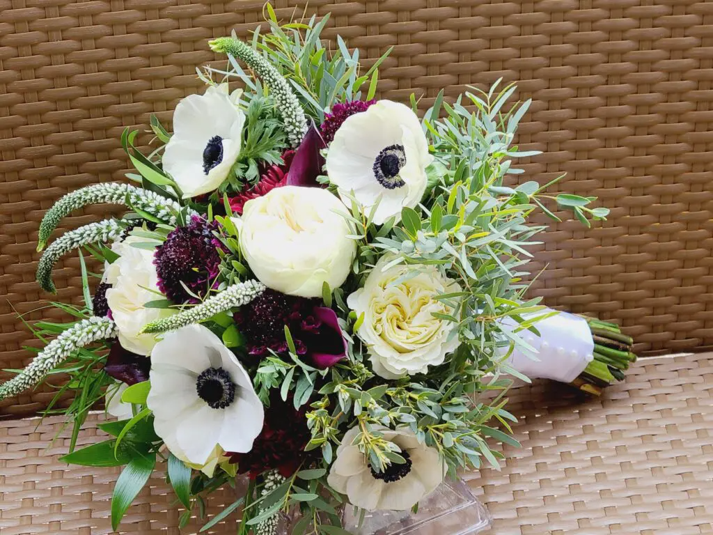 A bouquet of flowers is sitting on a wicker table.