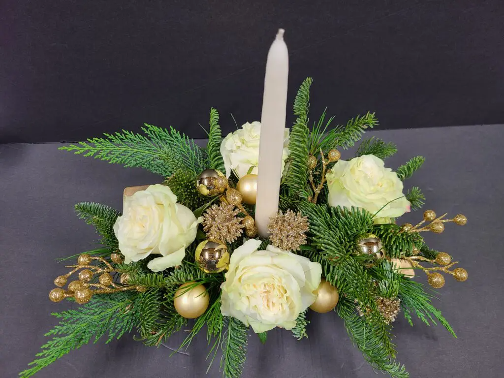 There is a candle in the middle of a flower arrangement.