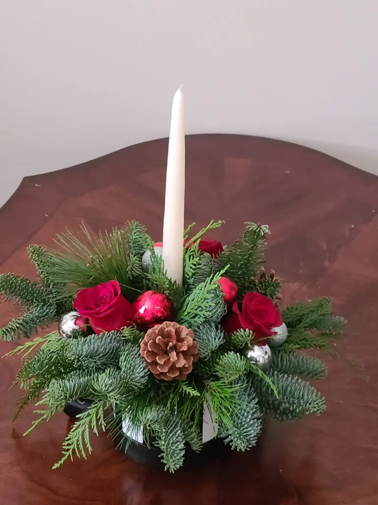 A christmas centerpiece with a candle in the middle is on a table.