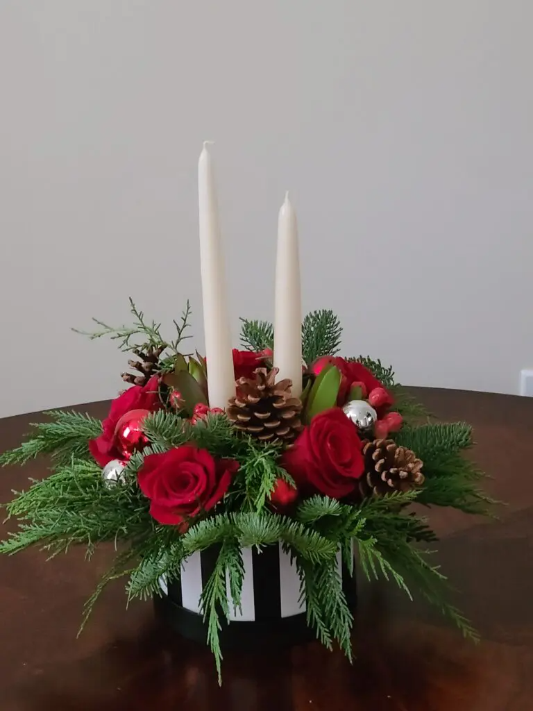 A black and white striped vase filled with flowers and candles