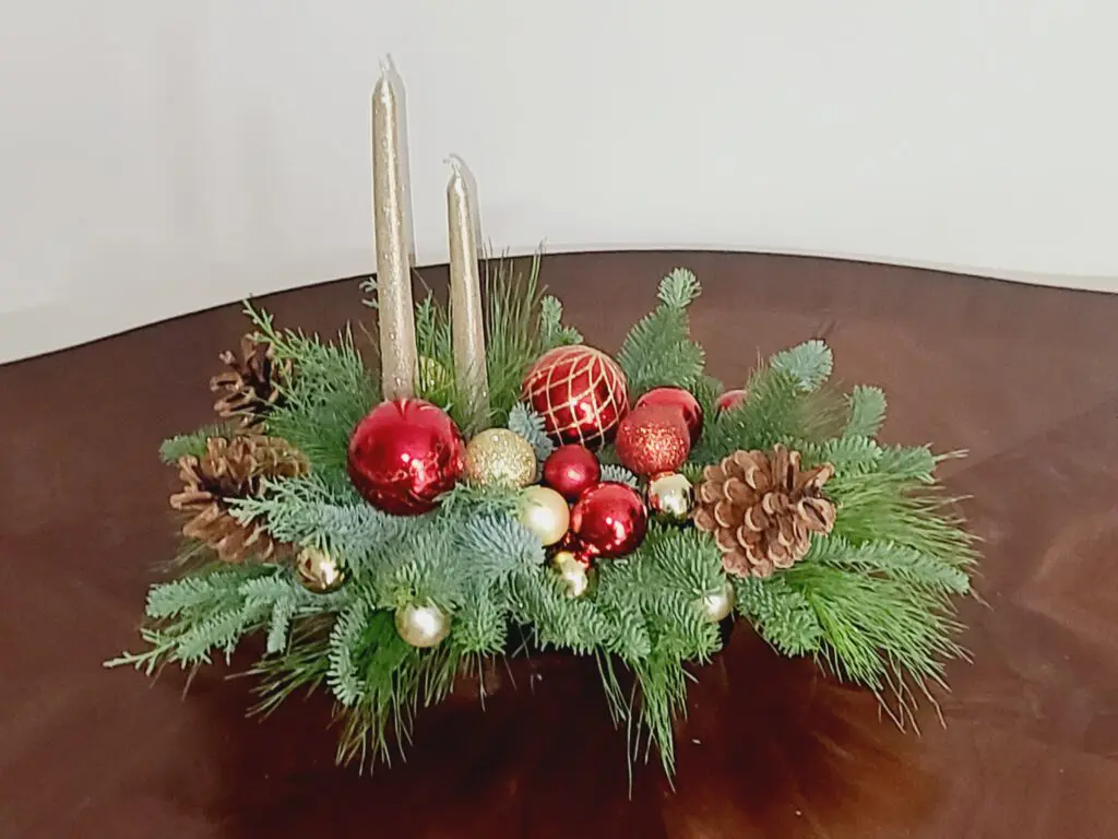 A christmas centerpiece is sitting on a wooden table.