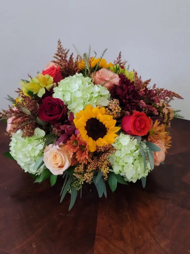 A bouquet of flowers is sitting on a wooden table.