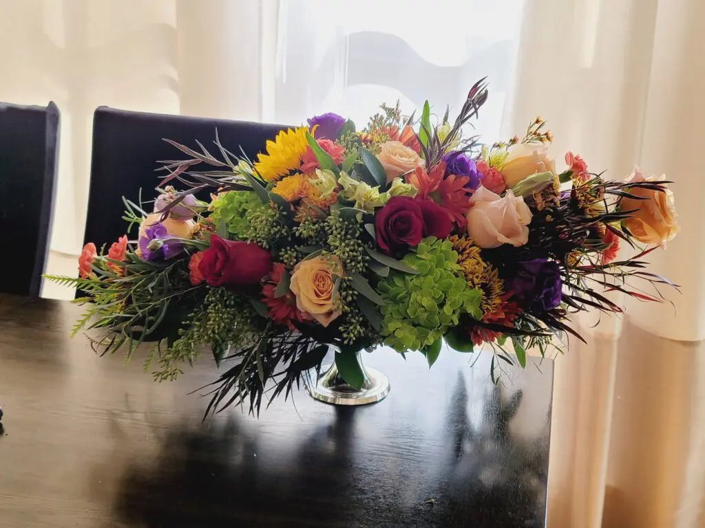 A vase of flowers is sitting on a table in front of a window.