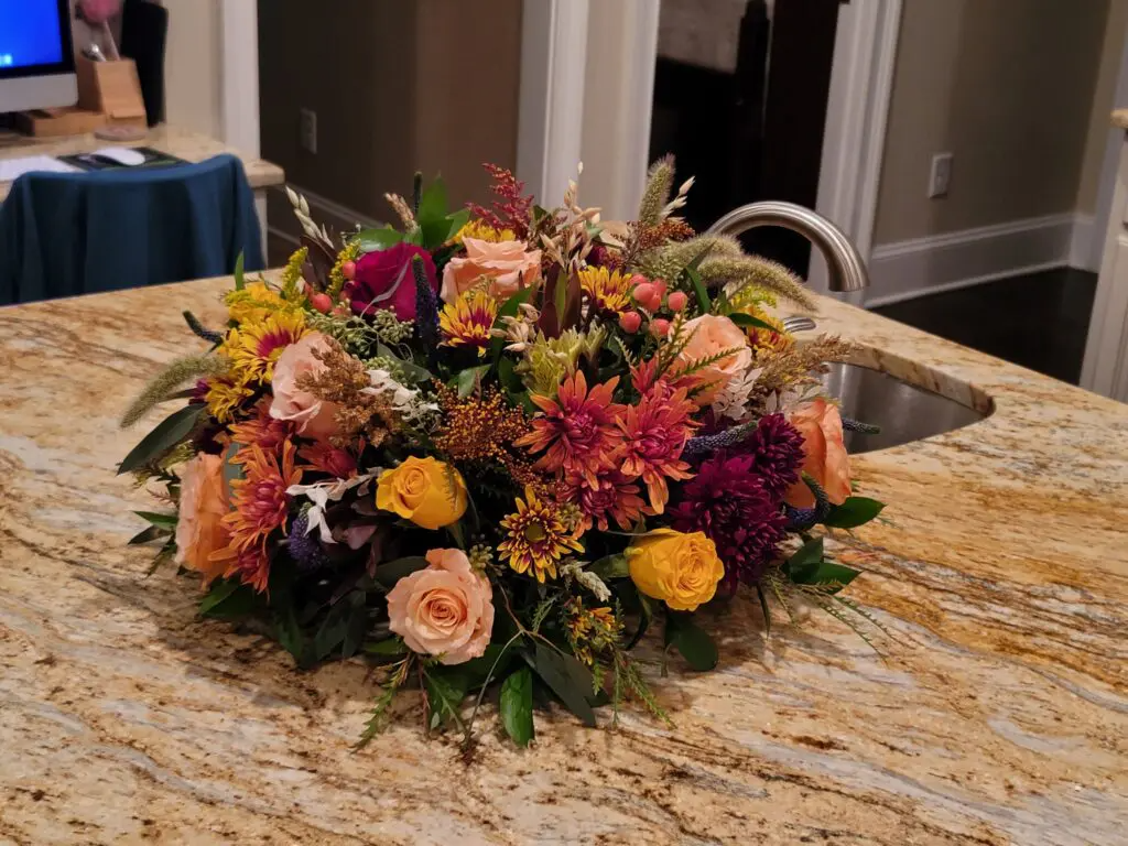 A bouquet of flowers is sitting on a granite counter next to a sink.