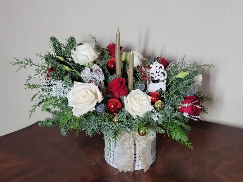 A vase filled with flowers and candles is sitting on a wooden table.