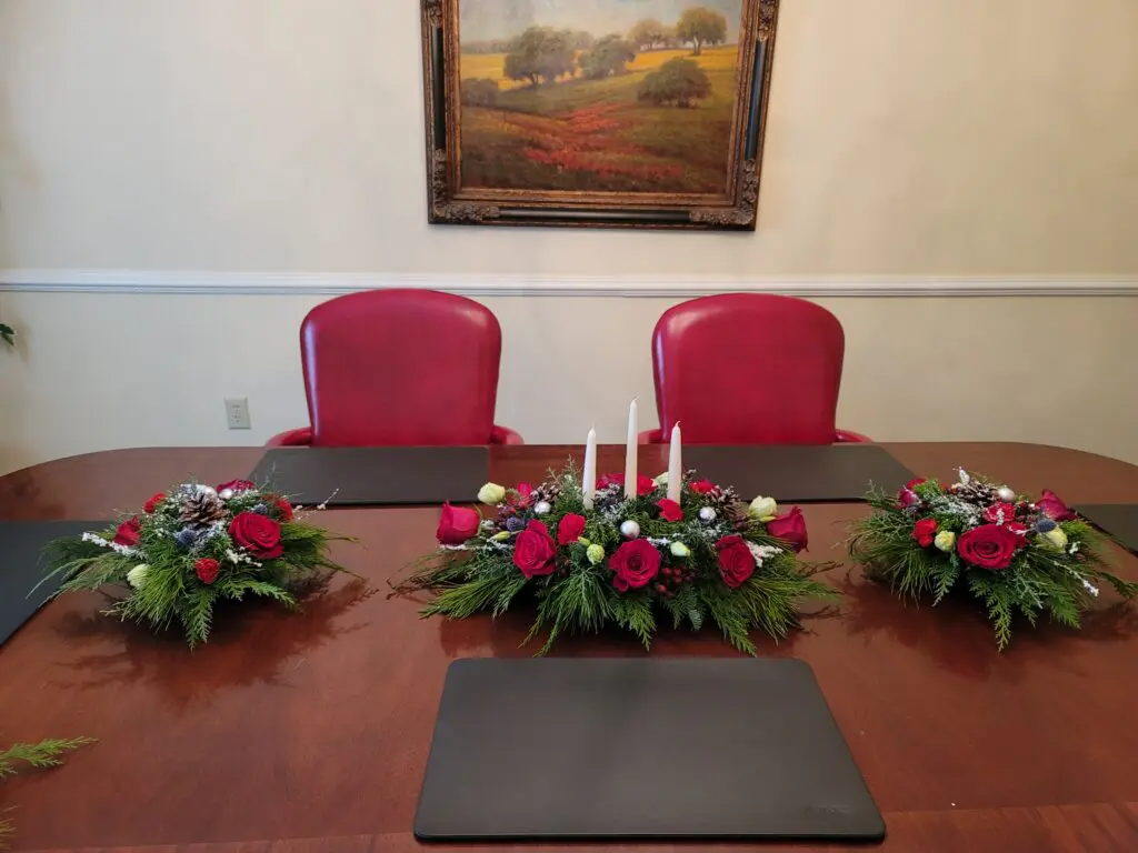 A conference table with flowers and candles on it.