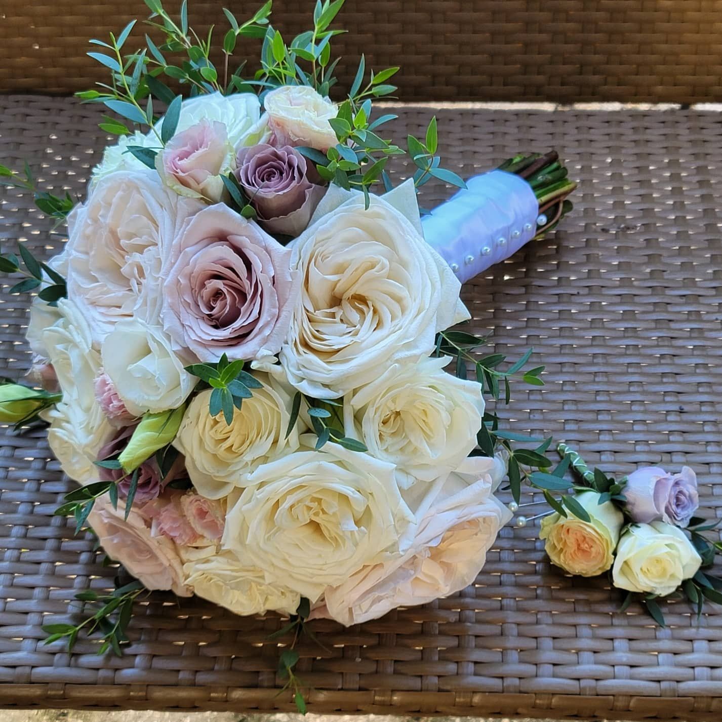 A bouquet of white roses and pink roses is sitting on a wicker table.