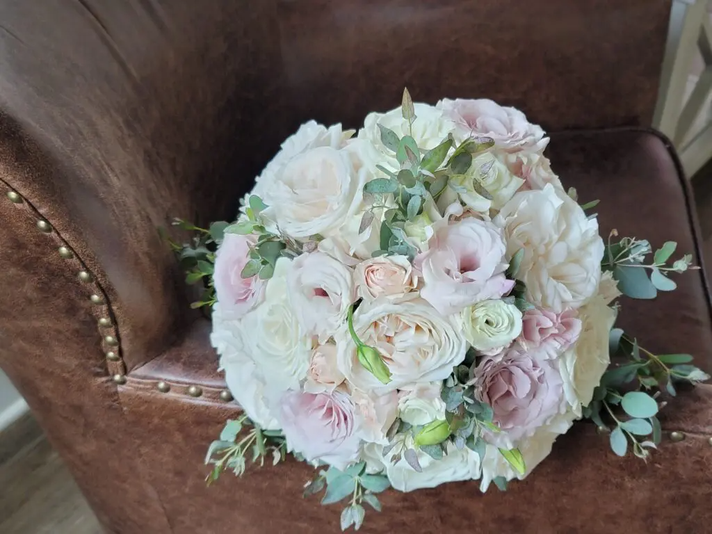 A bouquet of flowers is sitting on a brown leather chair.