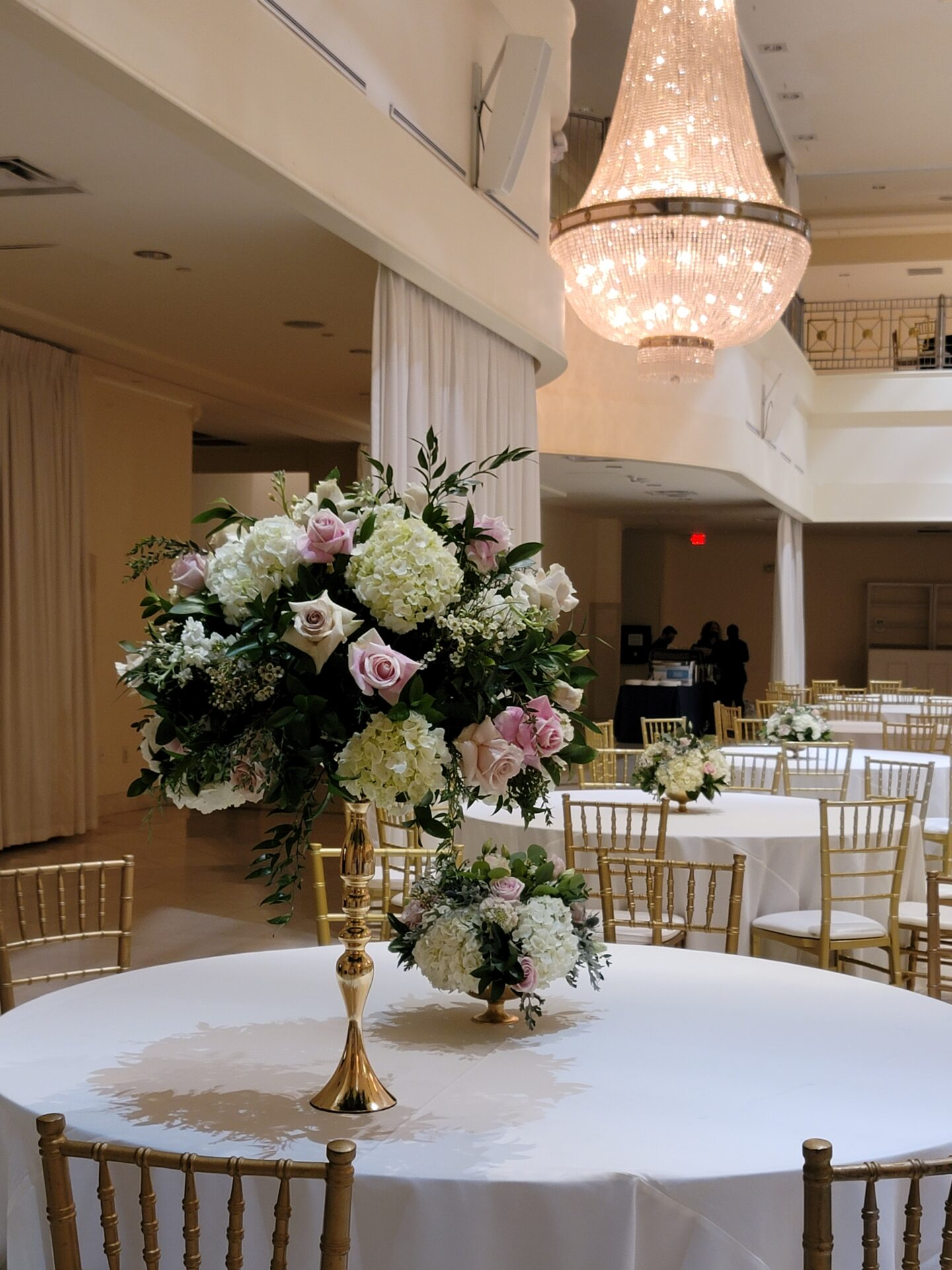 A table with a vase of flowers on it and a chandelier hanging from the ceiling.