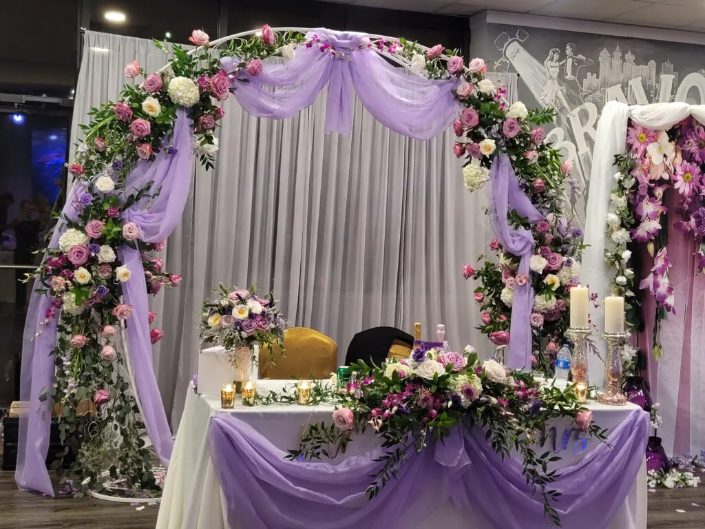 A table is decorated with purple flowers and candles.