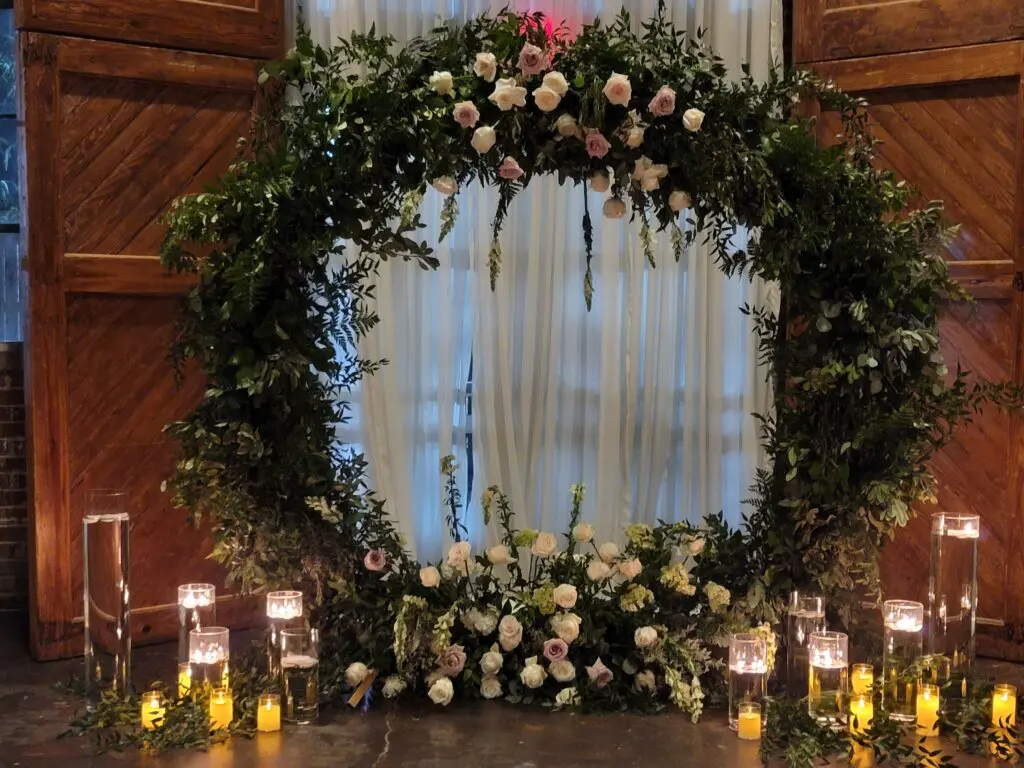 A wedding arch decorated with flowers and candles in a room.