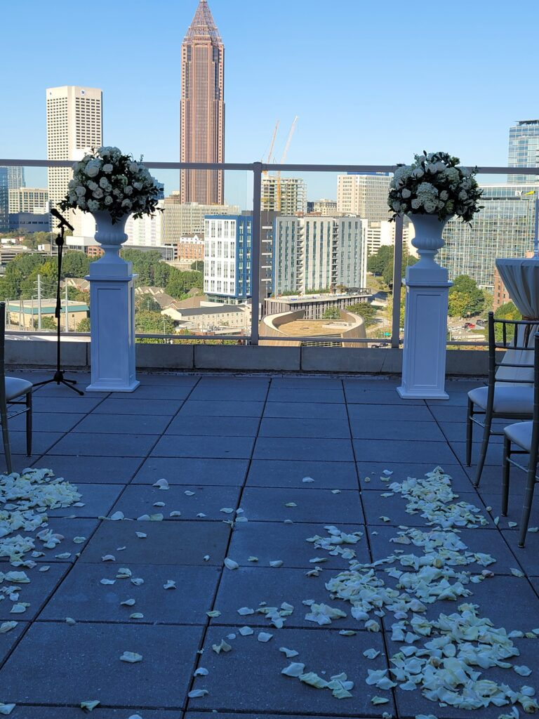 A wedding ceremony is taking place on a balcony overlooking the city