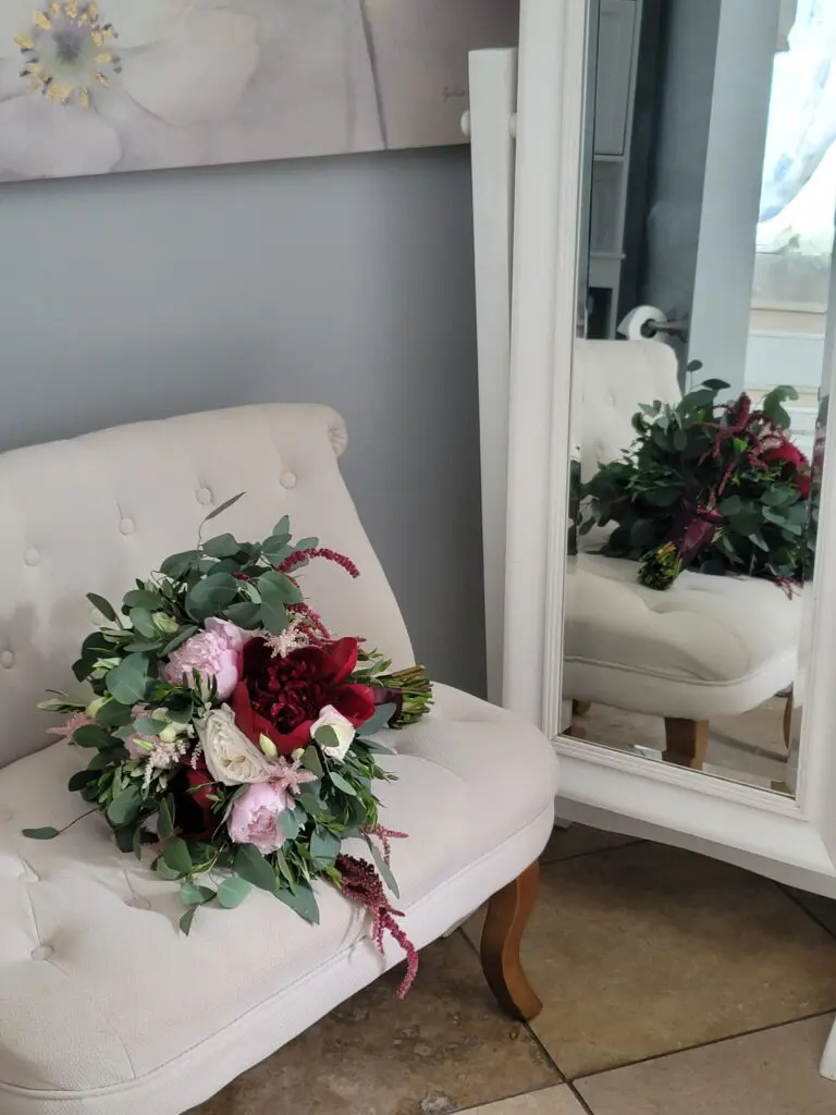 A bouquet of flowers is sitting on a chair in front of a mirror.