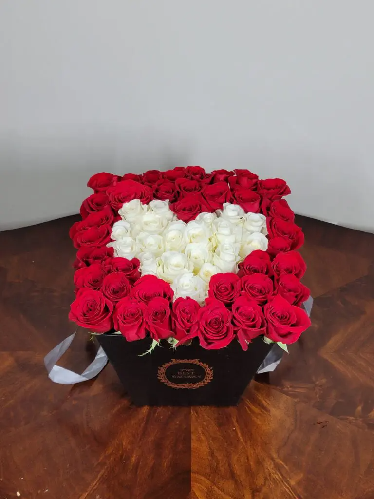 A box filled with red and white roses in the shape of a heart.