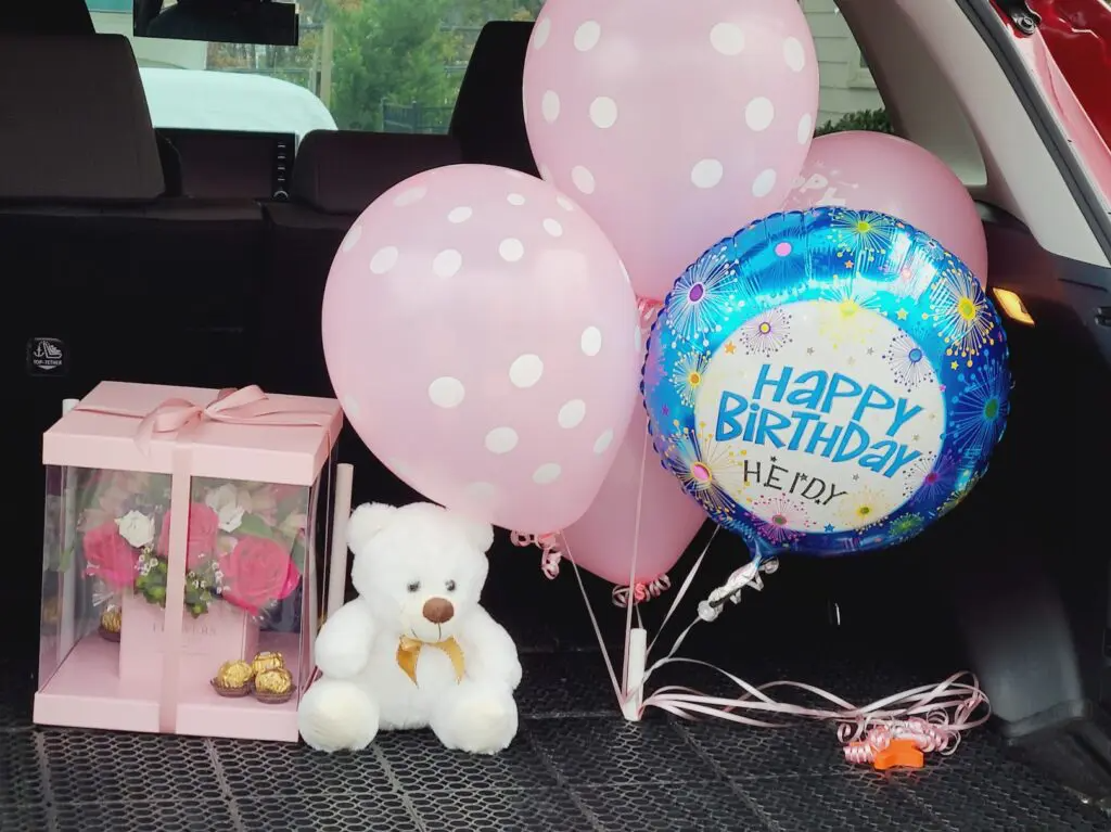 A happy birthday balloon is in the back of a car