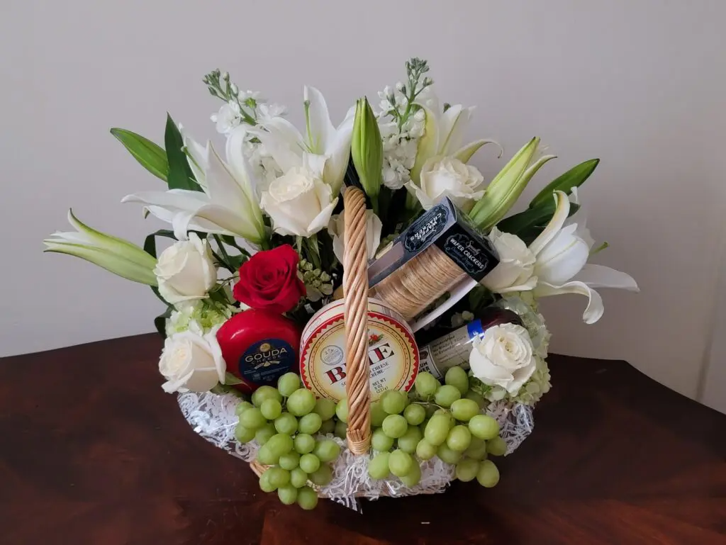 A basket filled with flowers and grapes on a table