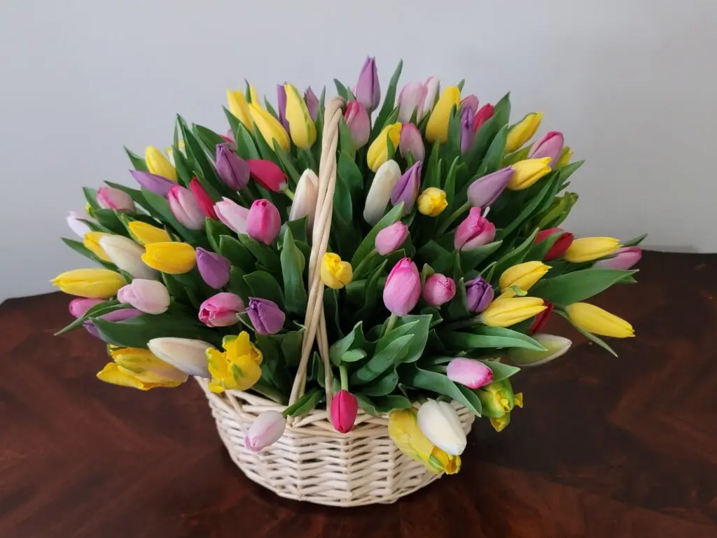A basket filled with lots of colorful flowers on a table