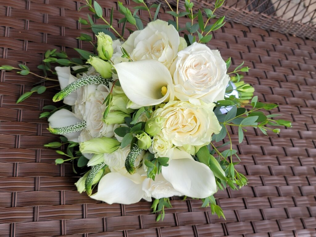 A bouquet of white flowers is sitting on a wicker table.