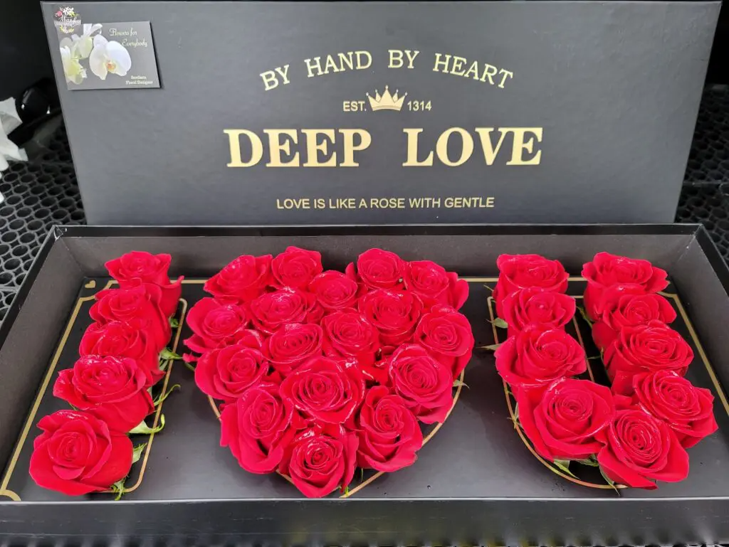 A box with red roses in the shape of a heart that says deep love