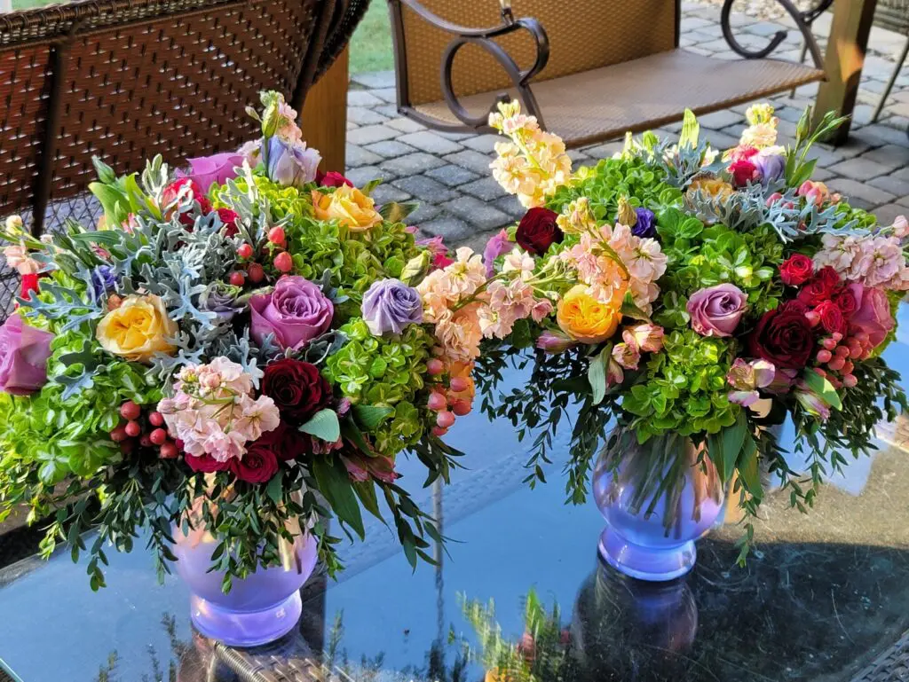 Two vases filled with flowers are sitting on a glass table.