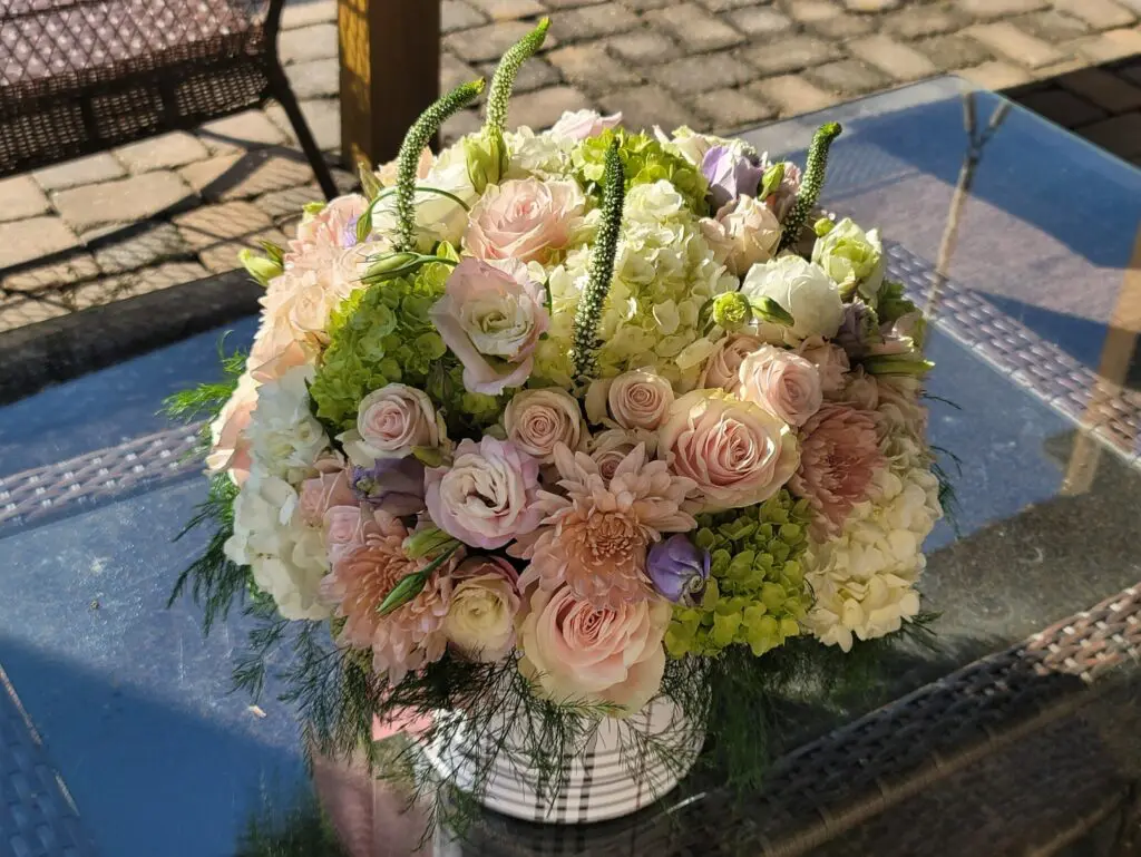 A vase filled with pink and white flowers is sitting on a glass table.