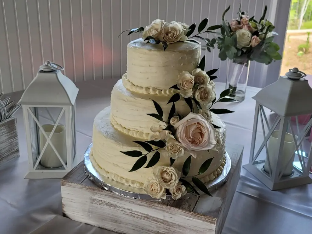 A wedding cake is sitting on top of a wooden box on a table.
