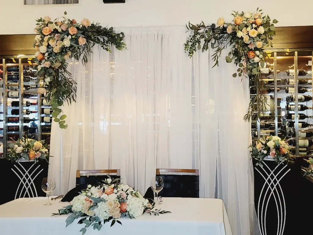 A table with flowers on it in front of a white curtain.