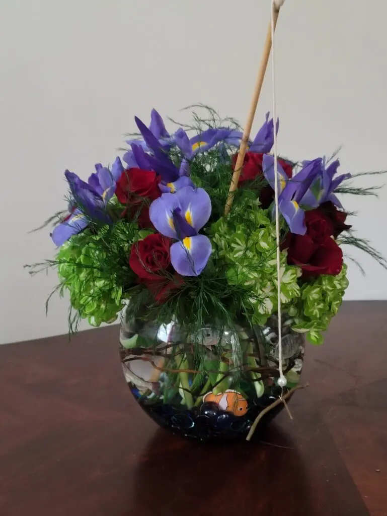 A fish bowl filled with purple and red flowers