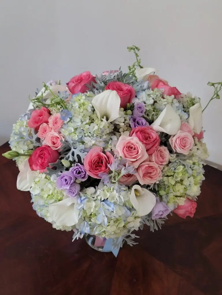 A large bouquet of flowers is sitting on a wooden table.