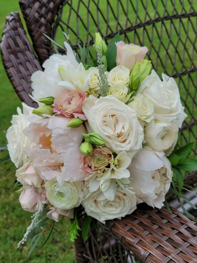 A bouquet of white flowers is sitting on a wicker chair.