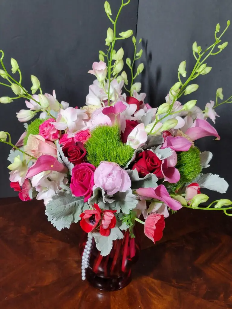 A vase filled with pink and red flowers on a wooden table