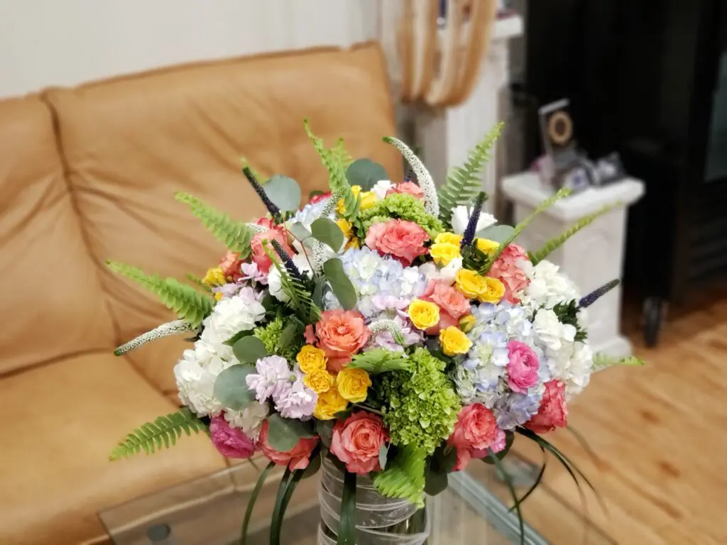 A vase filled with flowers is sitting on a glass table in a living room.