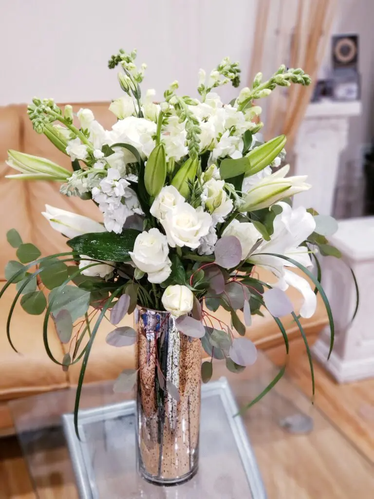 A vase filled with white flowers is sitting on a table.