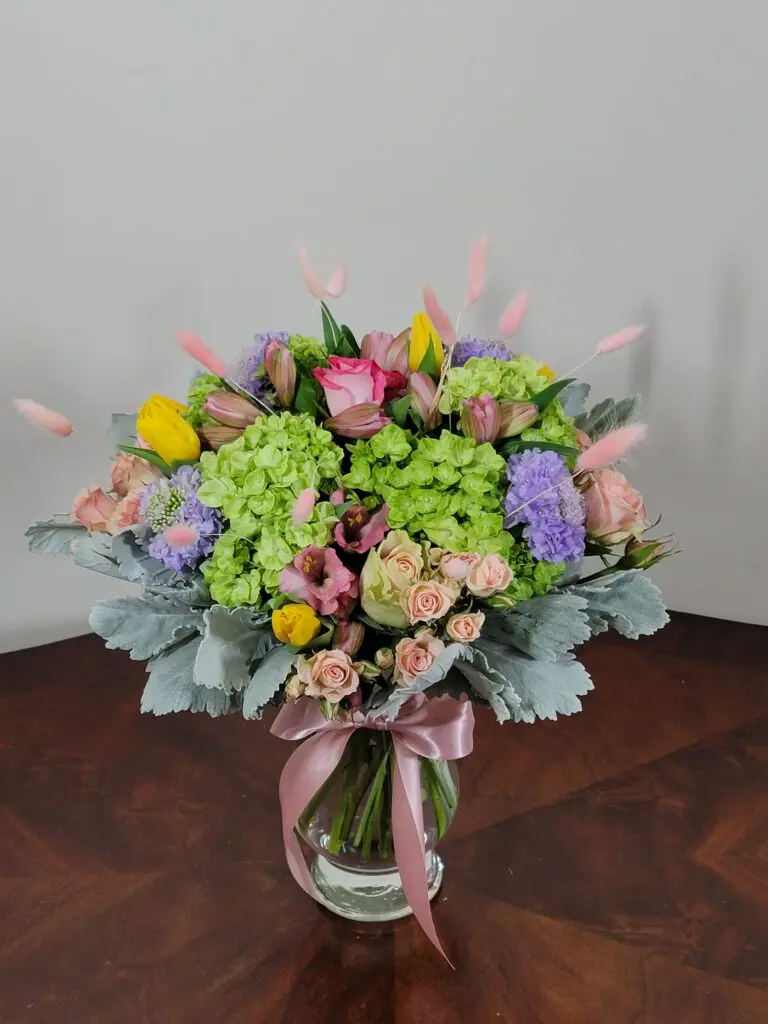A vase filled with flowers is sitting on a wooden table.