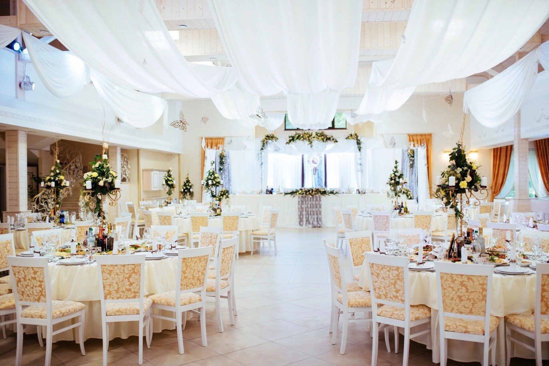 A large room with tables and chairs set up for a wedding reception.