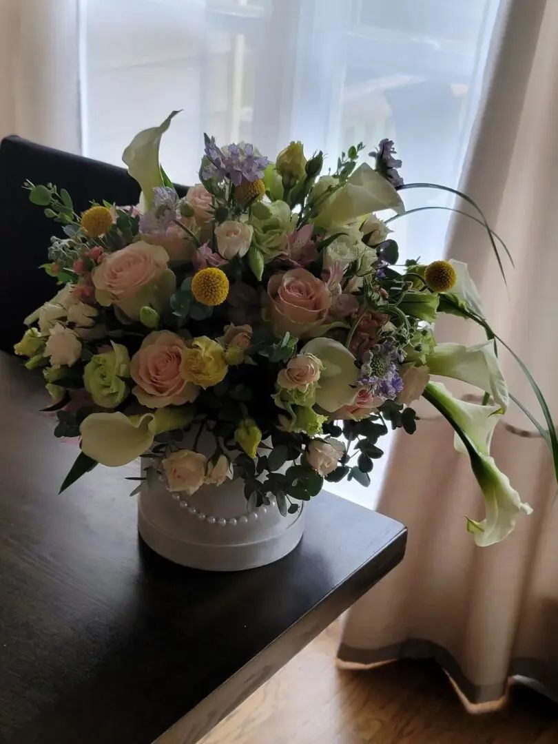 A vase filled with flowers is sitting on a table next to a window.