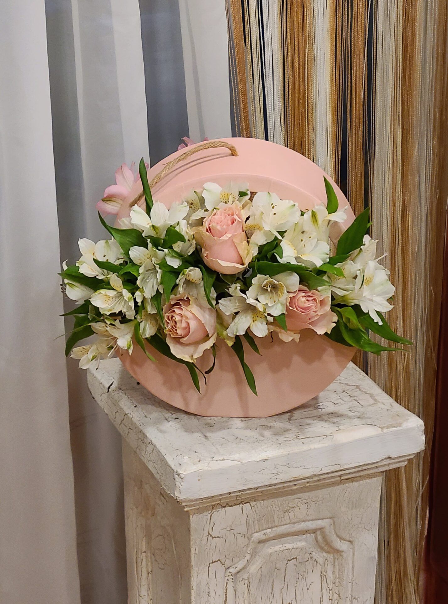 A pink box filled with flowers is sitting on a pedestal.