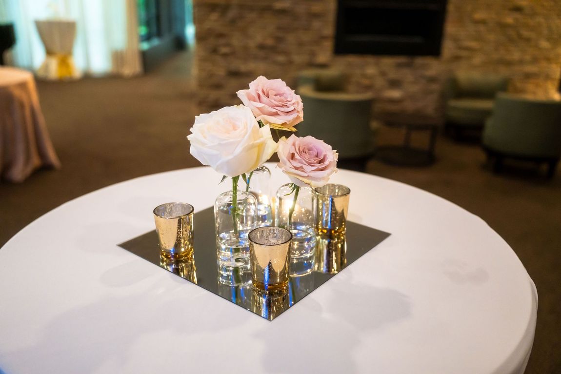 A table with a vase of flowers and candles on it.