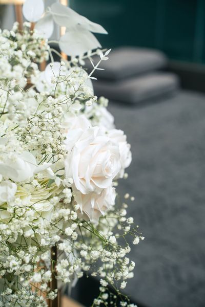 A close up of a vase filled with white flowers and baby 's breath.