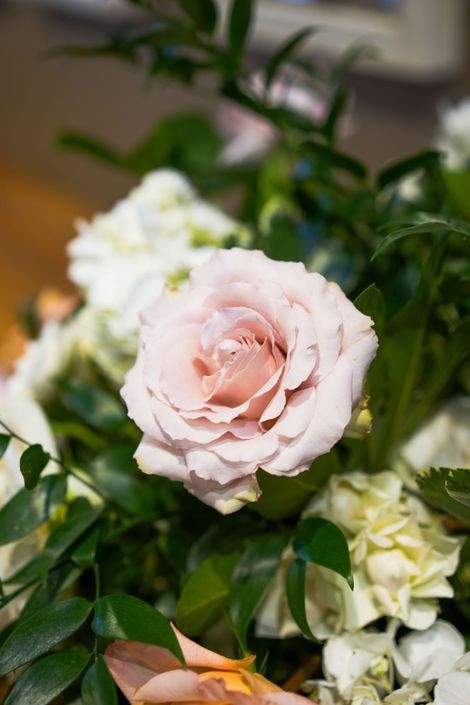 A close up of a pink rose in a bouquet of flowers.