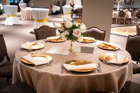 A table with plates , napkins , silverware and a vase of flowers on it.