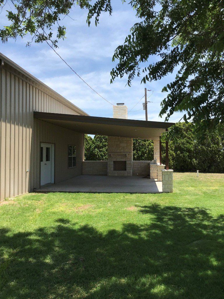 A large building with a covered porch and a fireplace in the backyard.