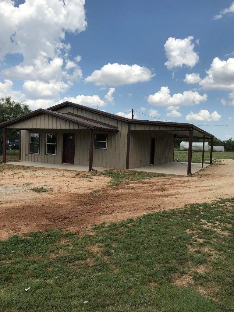 A house is sitting in the middle of a grassy field.