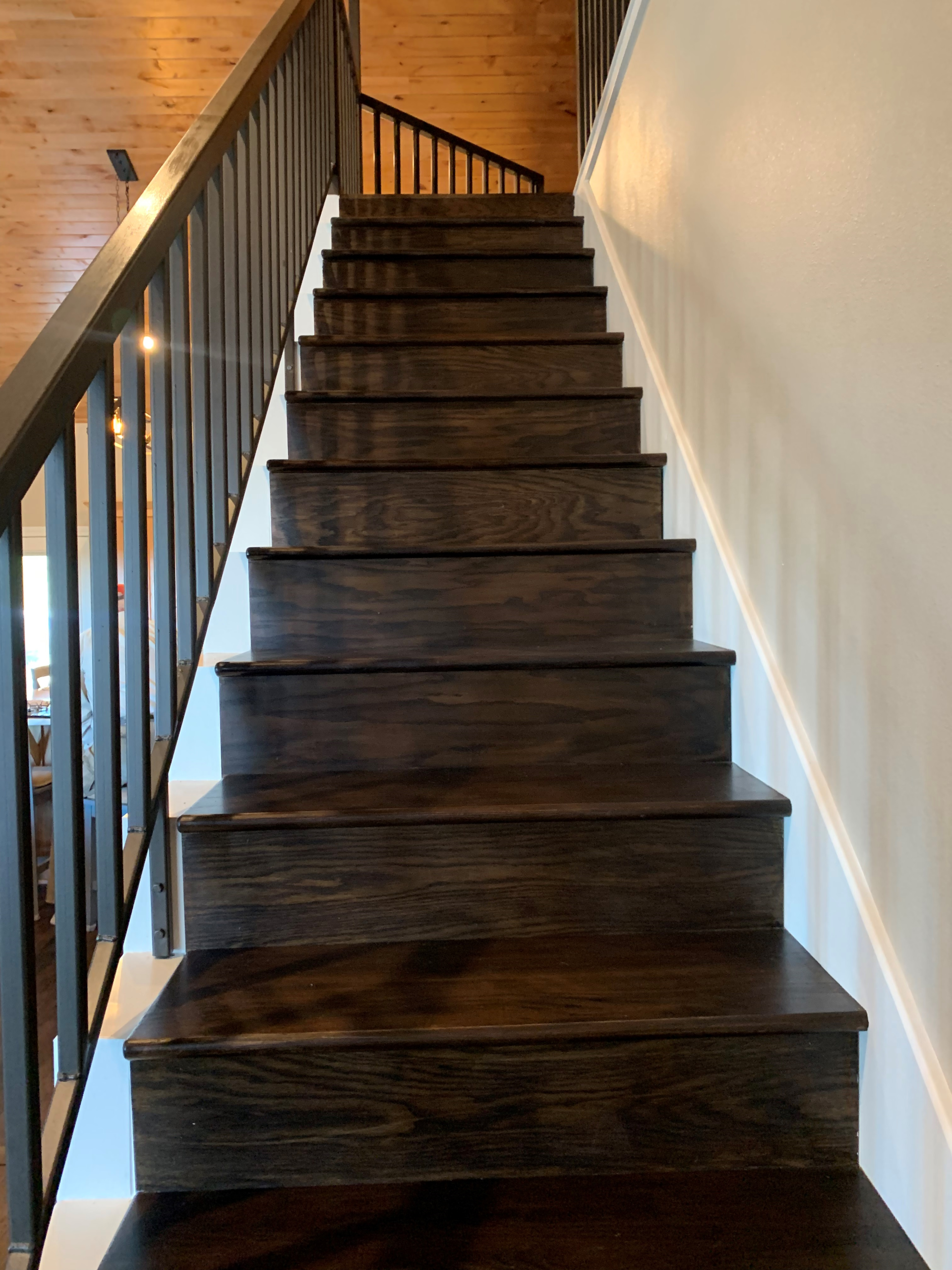 A wooden staircase with a metal railing leading up to the second floor of a house.