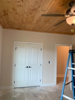 An empty room with a ceiling fan and a blue ladder